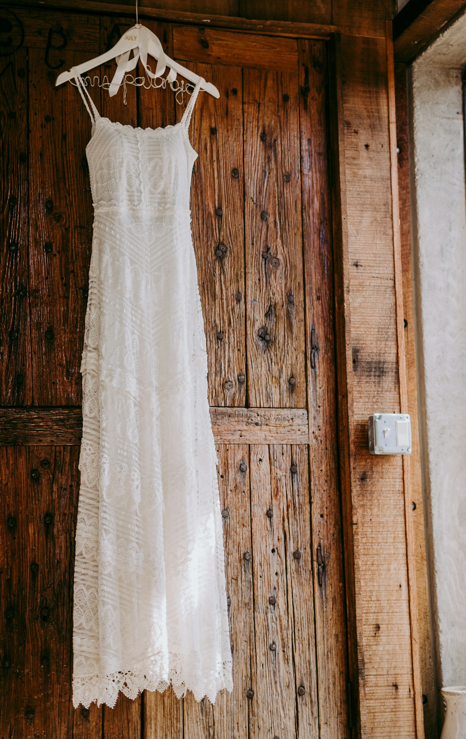 Weißes Brautkleid vor einer Holztür